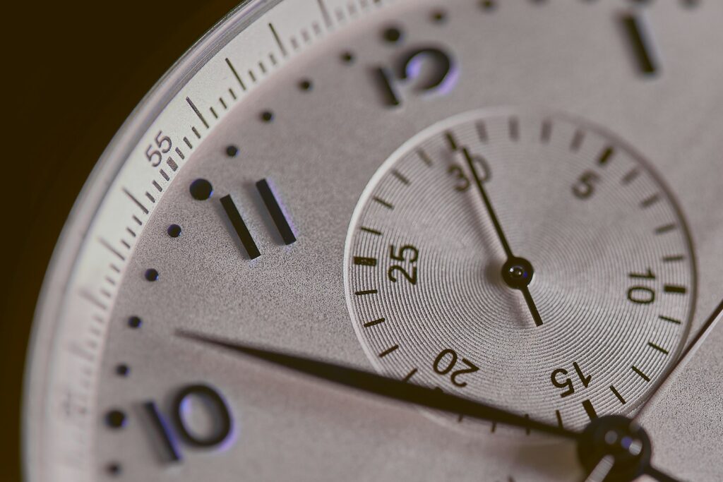 Photo by Agê Barros a close up of a silver watch face